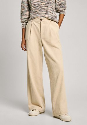 Beige weit geschnittene Hose aus strukturiertem Stoff, mit hoher Taille und Bundfalten, kombiniert mit einem mehrfarbigen Strickpullover.