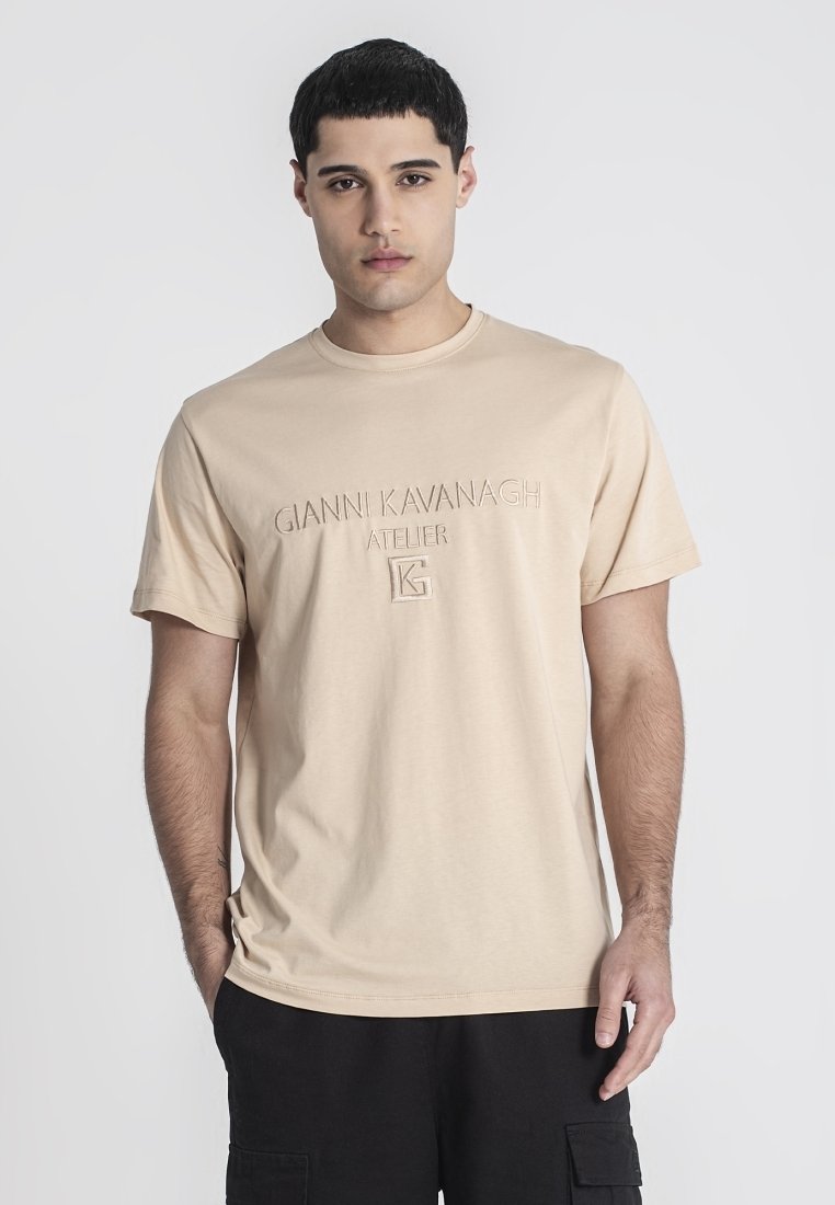 Beige bavlnené tričko s krátkymi rukávmi, na prednej strane s vyrazeným logom "Gianni Kavanagh Atelier". Hladký povrch a strih s okrúhlym výstrihom.