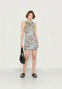 Vestido ajustado com padrão floral e decote redondo. As cores incluem verde, azul e bordô. Combinado com uma mala preta esandálias.
