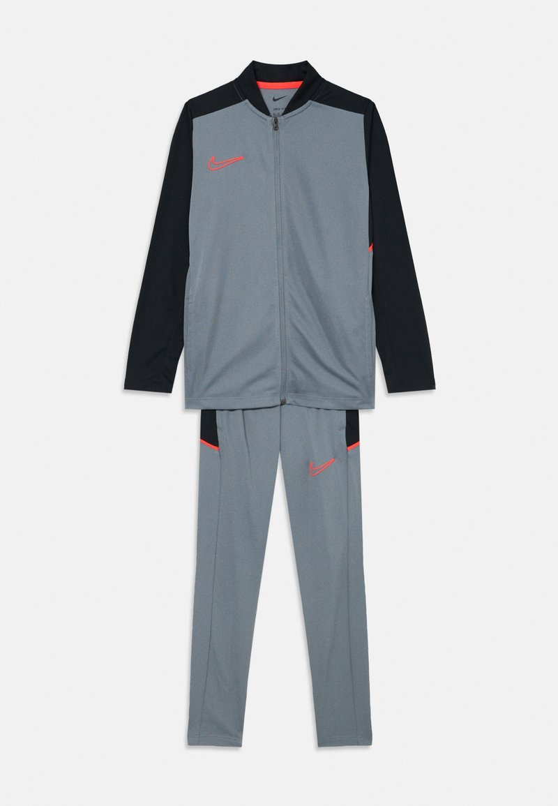 Grijze Nike trainingspak met een ritsjack met zwarte mouwen en rode accenten, gecombineerd met bijpassende broek met zijzakken.