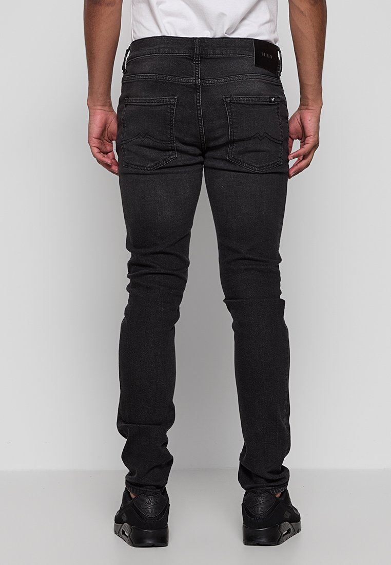 Czarne, slim-fit dżinsy wykonane z denimu, charakteryzujące się gładką teksturą, klasycznym przeszyciem oraz dwiema tylnymi kieszeniami z ozdobnymi szwami.