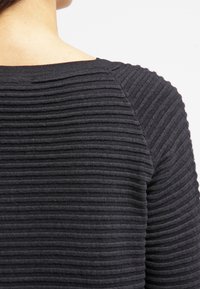 Schwarzer strukturierten Pullover mit horizontalen Rippmustern, runder Halslinie und einem lockeren Schnitt mit Raglanärmeln.