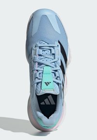 Zapatilla deportiva de color azul claro con parte superior de malla, detalles de franjas negras y acentos en verde menta en la lengüeta; con cuello acolchado y suela amortiguada.
