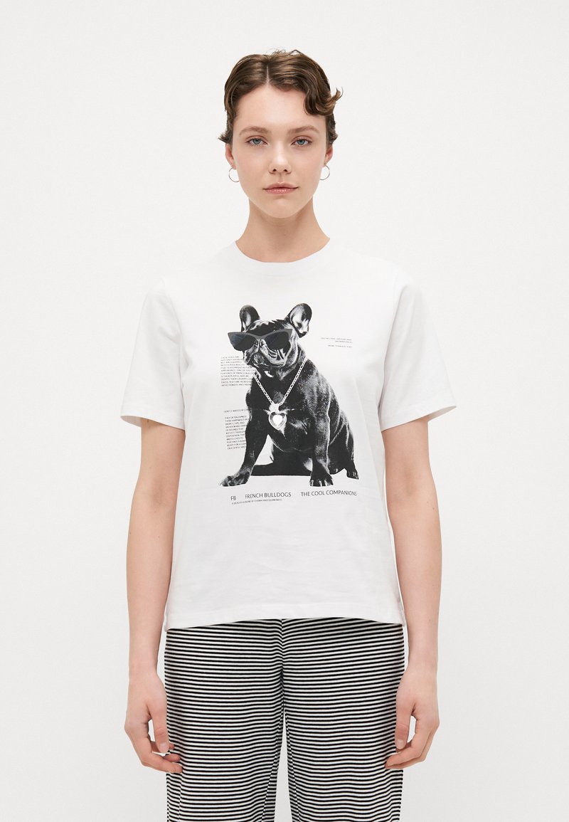 White t-shirt featuring a black and white graphic of a dog wearing sunglasses, with text and a decorative heart-shaped necklace. Striped pants included.