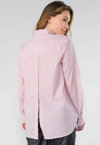 Long-sleeve button-up shirt featuring pink and blue vertical stripes, a pointed collar, and a back pleat for added movement.