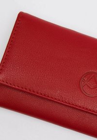 Portafoglio in pelle rossa con superficie testurizzata, caratterizzato da un logo impresso e cuciture a contrasto lungo i bordi. Design compatto.
