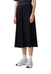 Gonna midi plissettata blu navy con una cintura etichettata "CASUAL IDENTITY," abbinata a scarpe da ginnastica bianche e calze corte. Presenta una texture liscia.
