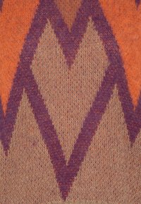 Textile tricoté avec un motif géométrique présentant des formes en chevrons orange et violet sur un fond beige, mettant en valeur une texture douce.