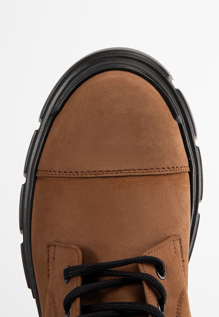 Braunes Wildleder-Schuhmodell mit schwarzer Gummisohle und Akzenten. Verfügt über eine runde Zehenform, tonales Nähen und schwarze Schnürsenkel. Die Draufsicht zeigt das Design.