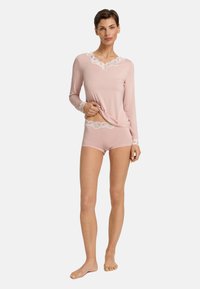 Conjunto de loungewear de color rosa claro que incluye una camiseta de manga larga y pantalones cortos, adornado con un borde de encaje blanco en el escote y los puños. Textura de tela suave.