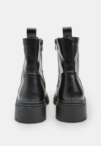 Stivali neri in pelle fino alla caviglia con un design elegante, chiusura con zip, tacco rialzato e suole testurizzate, dotati di linguette sul retro per una facile vestibilità.