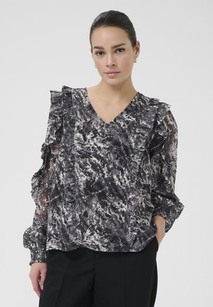 Zwart-witte blouse met een patroon, rimpelende schouders, V-hals en elastische manchetten, gemaakt van een gestructureerde, semi-doorzichtige stof.