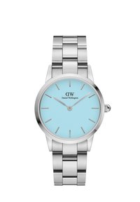 Hõbedane roostevabast terasest käekell ümmarguse näo, taevasinise kellapaneeli, hõbedaste tunni näitajate ja "Daniel Wellington" logo ning.