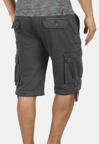 Gray cargo shorts with multiple side pockets, button closures, and a relaxed fit. Made from soft, durable fabric with visible stitching.
