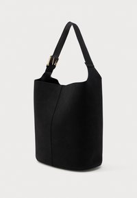 Sort læderbøtte taske med justerbar skulderrem og guldfarvet spænde, stående oprejst på en hvid baggrund.