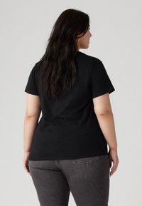 Tricou negru cu mânecă scurtă, cu o croială lejeră, fabricat din bumbac moale, având un guler rotund clasic și o tivă dreaptă.