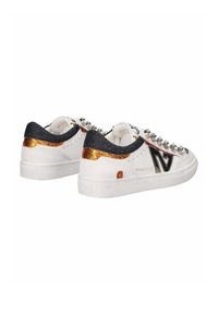 Sneakers bianchi con accenti neri e dorati metallici, materiali testurizzati, borchie decorative sui lacci e una forma della punta rotonda.