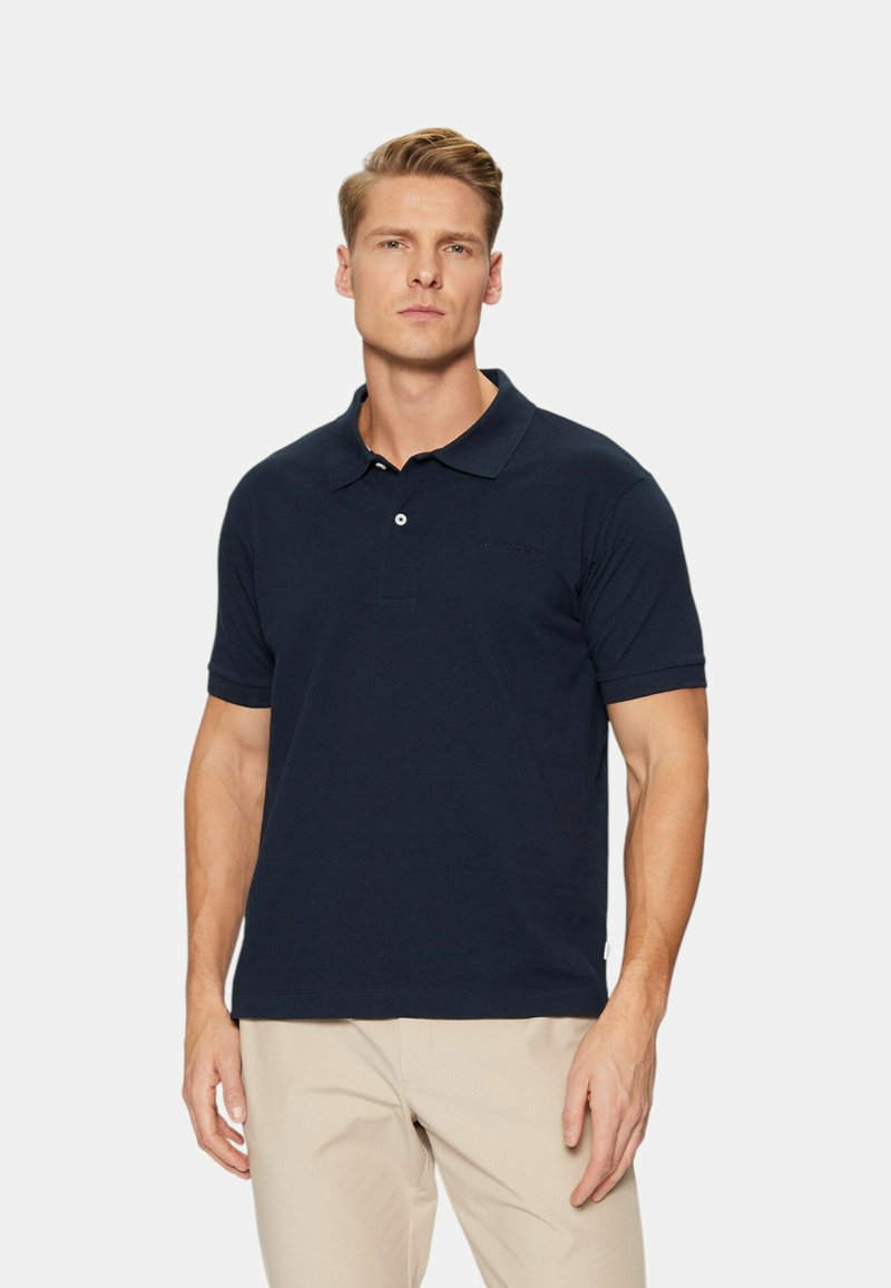 Polo blu navy in misto cotone, con colletto classico, patta con due bottoni e maniche corte. Logo discreto sul petto.