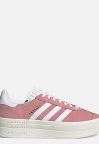 Zapatillas Adidas Gazelle de ante rosa con rayas blancas, cordones blancos, lengüeta en relieve blanca y suela blanca gruesa y texturizada.