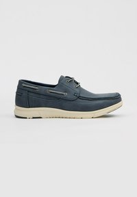 Zapatos de barco para hombre en piel azul con un acabado texturizado, suela de goma blanca y ojales en tono plateado para los cordones. Diseño casual y de perfil bajo.