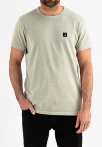 Lichtgroene katoenen t-shirt met korte mouwen en een ronde hals, met een klein zwart logo op de linkerborst. Draag het met zwarte broek.