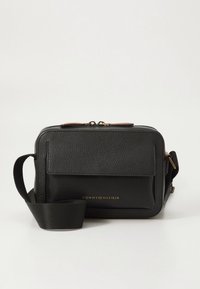 Black leather crossbody bag with textured finish, front flap pocket, gold logo detailing, and adjustable fabric strap. Zipper closure.