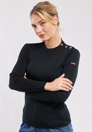 Haut noir à manches longues côtelé avec un col rond. Comprend trois boutons décoratifs à l'épaule et un petit logo sur la manche.