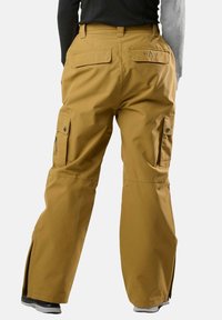 Braune Cargo-Hosen mit lockerer Passform, hergestellt aus wasserabweisendem Material. Zu den Merkmalen gehören mehrere Taschen und Reißverschlüsse an den Knöcheln.