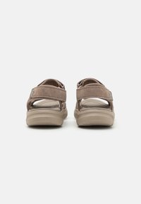 Brune semskede sandaler med justerbare remmer, polstret beige såle og teksturert yttersåle for grep. Har en subtil merkevaredetalj.
