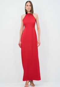 Rød halterneck maxi-kjole, glat stof, tætsiddende liv, flagrende skørt, minimal syning, båret med nude strop hæle.