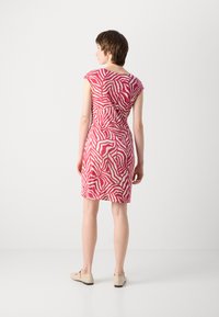 Robe sans manches en rose et crème, arborant un motif abstrait de zèbre. Elle est ajustée, arrive au genou avec une texture douce et un design simple.