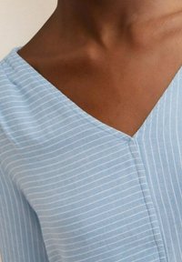 Tessuto blu chiaro a righe con design a V, che presenta una sottile trama e sottili righe bianche. Cuciture pulite lungo i bordi.