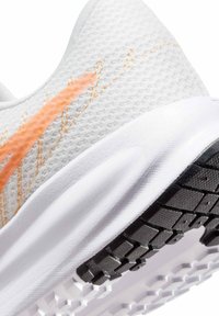 Hvid atletiksko med et tekstureret mesh-overdel, prydet med en orange accentstribe, polstret sål og sort gummisål med grip-mønstre.