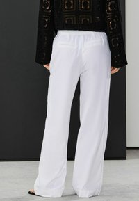 Weiß, weit geschnittene Hosen aus leichtem Stoff mit lässiger Passform. Elastischer Bund mit zwei Gesäßtaschen.