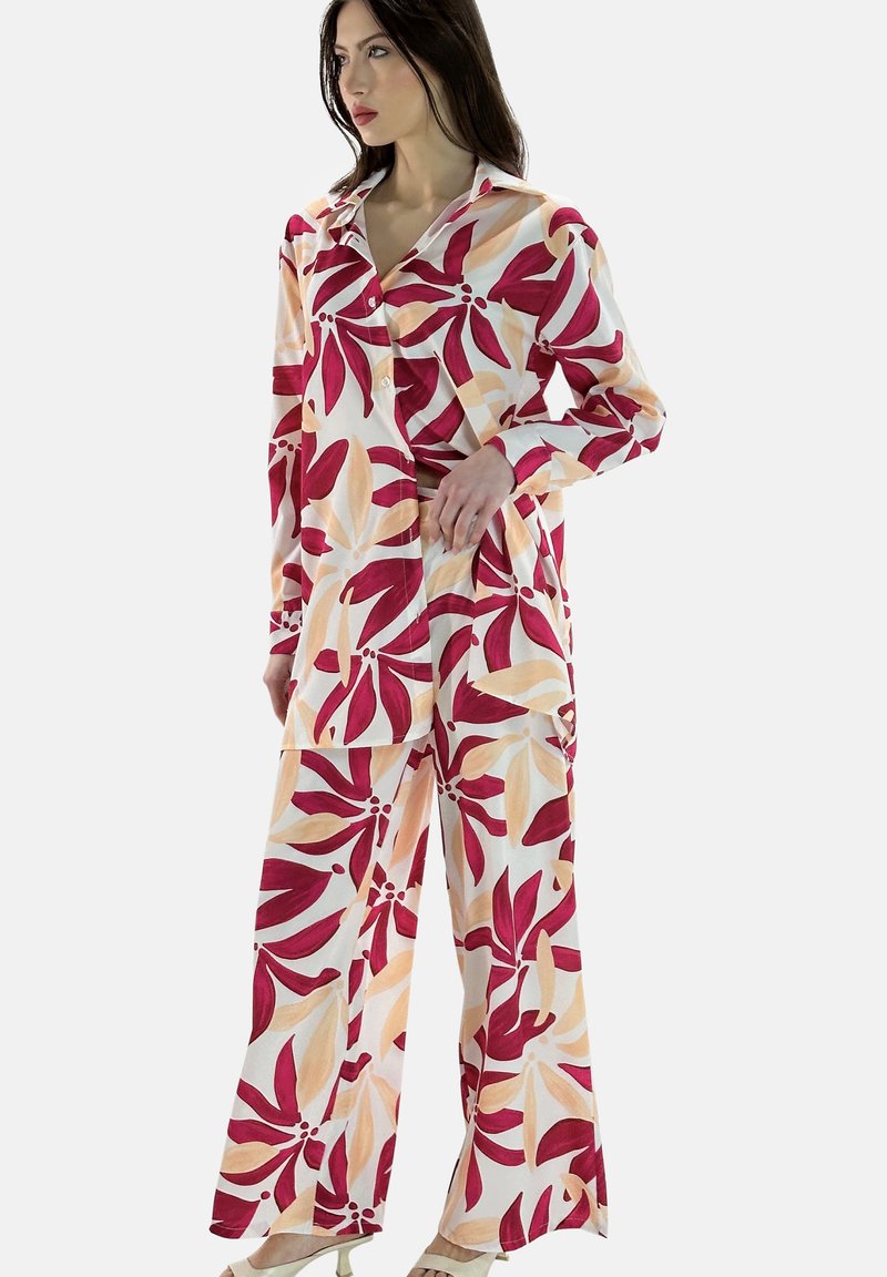 Blomsterprintet hjemmebeklædning bestående af en langærmet skjorte og brede bukser i hvid med røde og orange bladmønstre, lavet af letvægtsstof.
