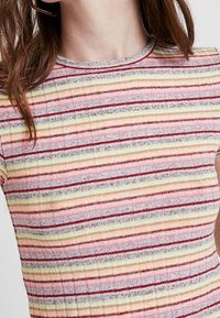 Krátký rukáv, pruhovaný top v růžové, žluté a červené barvě. Texturovaná ribbed tkanina s jemným leskem a kulatým výstřihem.