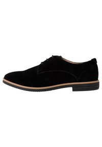 Chaussure habillée en daim noir avec un bout arrondi, présentant un détail de couture subtil et une semelle intermédiaire contrastante couleur tan, reposant sur une semelle extérieure en caoutchouc noir.