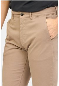 Chino beige realizzati in cotone con una texture liscia. Presentano tasche anteriori, chiusura con bottone e passanti per cintura. Design a vestibilità classica.