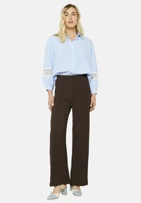 Light blue striped button-up shirt with lace accents at the sleeves, paired with brown wide-leg pants and two-tone block-heel shoes.
