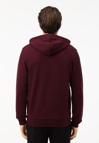 Felpa bordeaux con cappuccio regolabile, maniche lunghe e polsini a costine. Realizzata in tessuto morbido e liscio, con una vestibilità comoda.