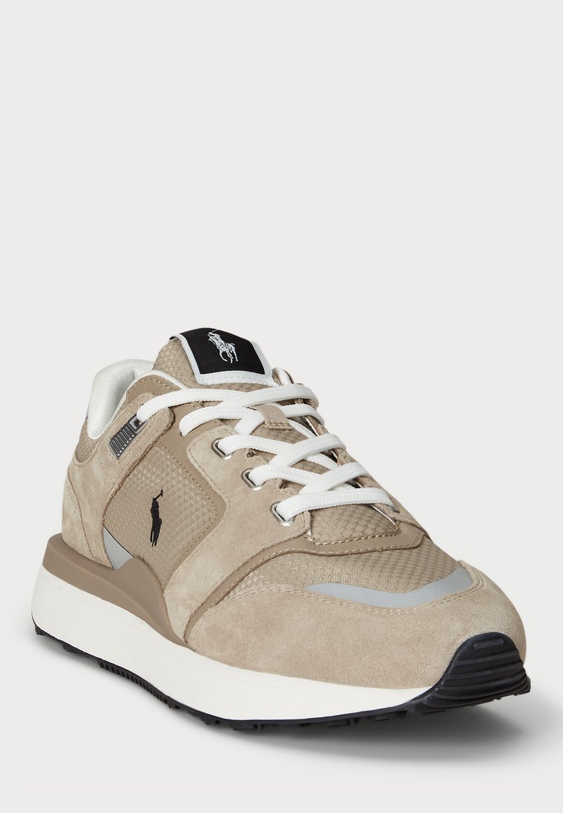 Zapatillas de ante y malla en beige y marrón con cordones blancos, suela negra y una etiqueta de logo en blanco y negro en la lengüeta.