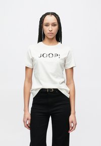 Λευκό βαμβακερό t-shirt με μαύρο γράφημα "JOOP!", κοντά μανίκια, λαιμόκοψη τύπου crew. Συνδυασμένο με μαύρο ψηλόμεσο παντελόνι και μαύρη ζώνη.