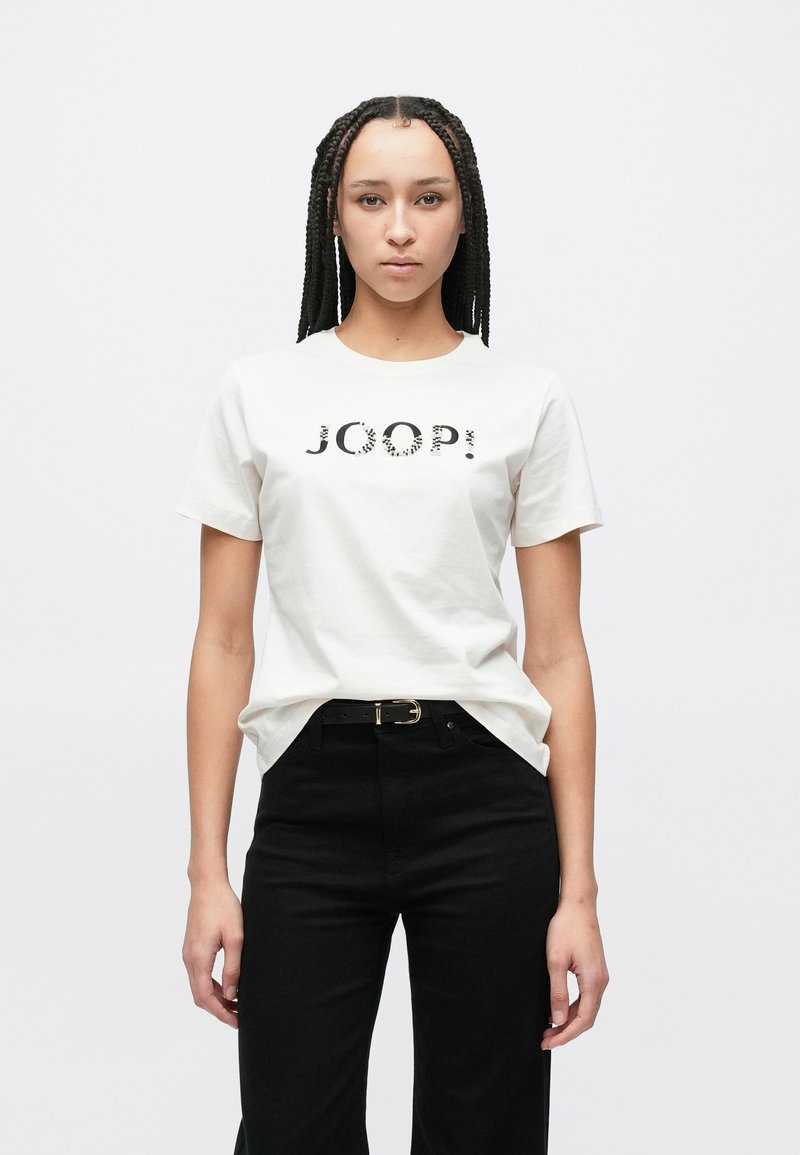 Λευκό βαμβακερό t-shirt με μαύρο γράφημα "JOOP!", κοντά μανίκια, λαιμόκοψη τύπου crew. Συνδυασμένο με μαύρο ψηλόμεσο παντελόνι και μαύρη ζώνη.