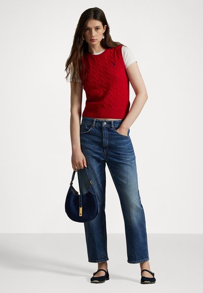 Pulover fără mâneci, tricotat în relief, de culoare roșie, purtat peste un tricou alb, combinat cu blugi lejeri, de culoare albastră, și o geantă de umăr de culoare bleumarin. Sandale plate negre.