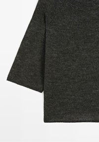 Pull en maille gris foncé à manches longues vu de face, mettant l'accent sur la texture et les détails partiels des manches et de l'ourlet.