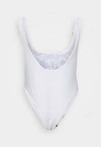 Bijela jednodelna kupaćica s dubokim V-izrezom, širokim naramenicama i glatkom teksturom. Unutrašnjost ima lagani cvjetni uzorak.