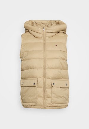 Chaleco acolchado sin mangas beige con capucha, cremallera frontal, dos bolsillos con solapa y botón a presión, y pequeño logo rojo, blanco y azul en el pecho.