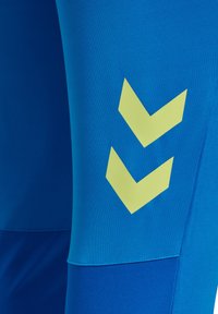 Felblauwe stof met twee gele chevronvormige pijlen die naar beneden wijzen aan de rechterkant.