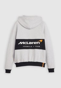 Szara bluza z kapturem z czarnym paskiem z tyłu, na którym widnieje napis "McLaren Formula 1 Team" w białym kolorze, uzupełniony pomarańczowym logo.