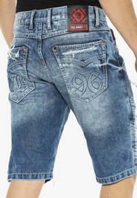 Jeans-Shorts in verblichenem Blau mit ausfransten Details. Verfügt über zwei Gesäßtaschen mit eingeprägten Zahlen und Nähten am Bund.